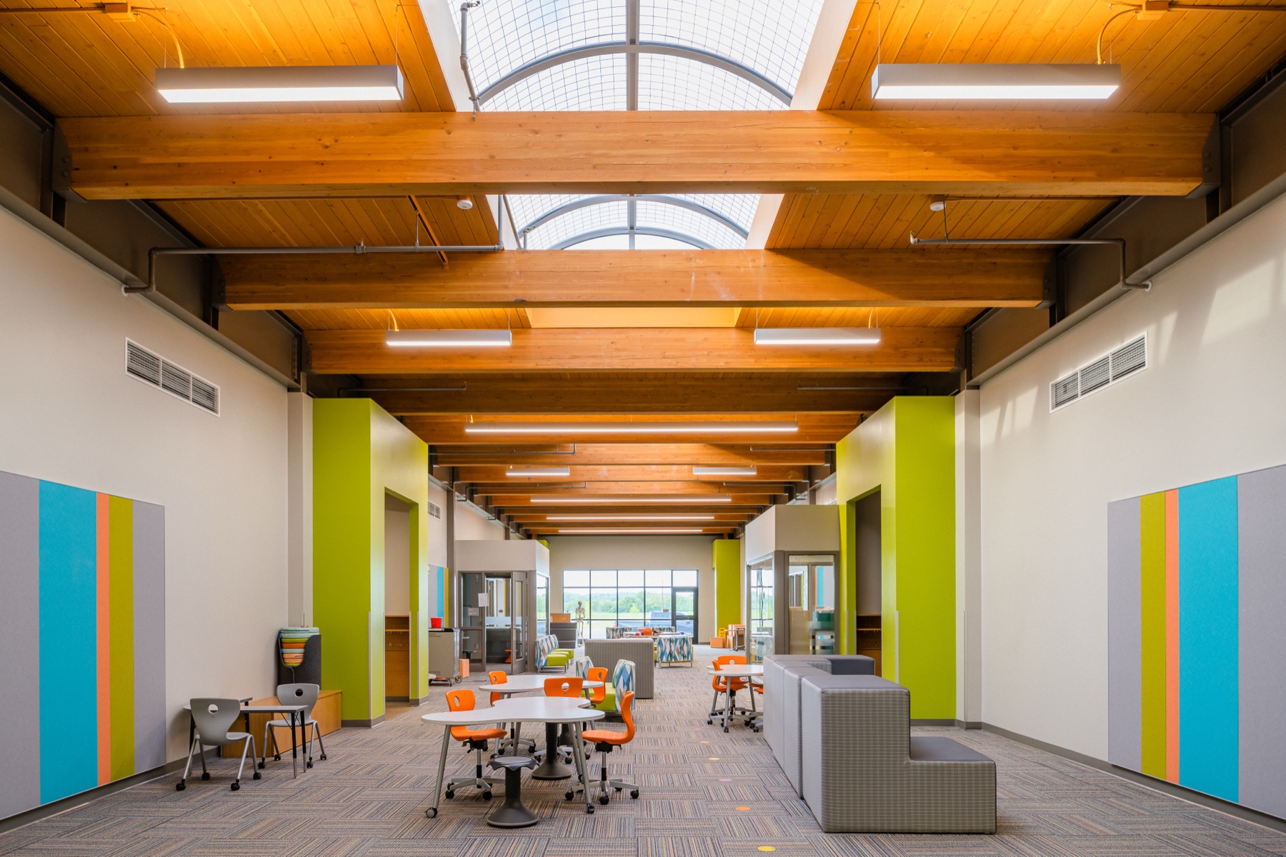 Students working in a school learning commons with exposed wood ceiling beams and a skylight