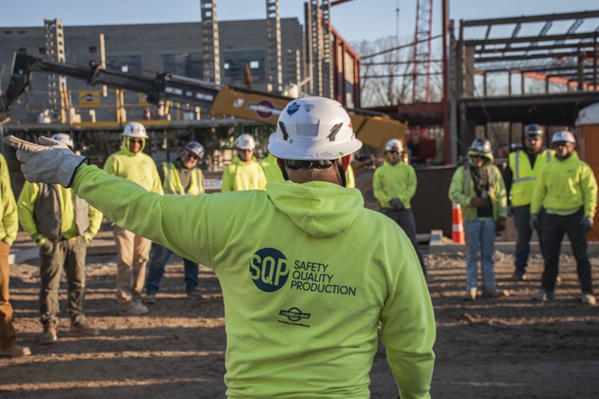 Miron foreman in an SQP hoodie directing a crew on a jobsite