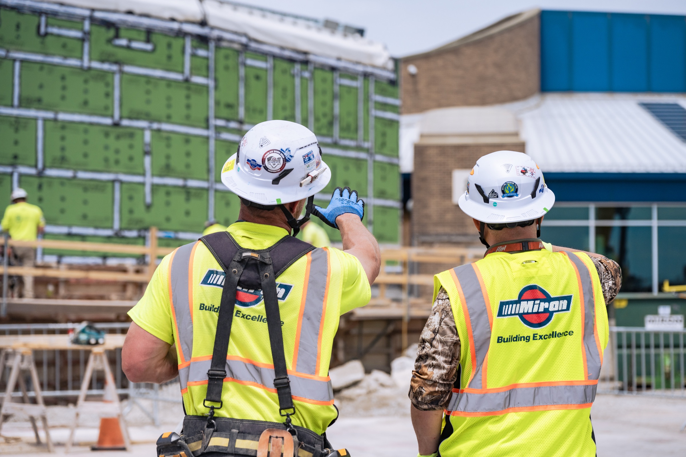 Two Miron workers in hard hats inspecting a building under construction