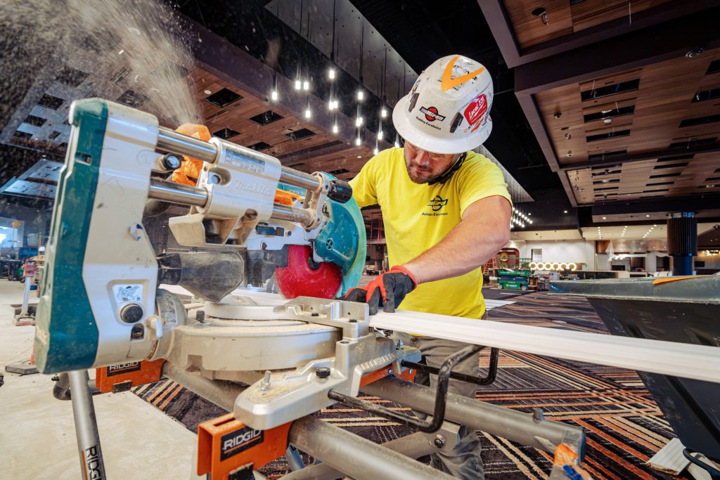 Miron carpenter cutting trim on a miter saw