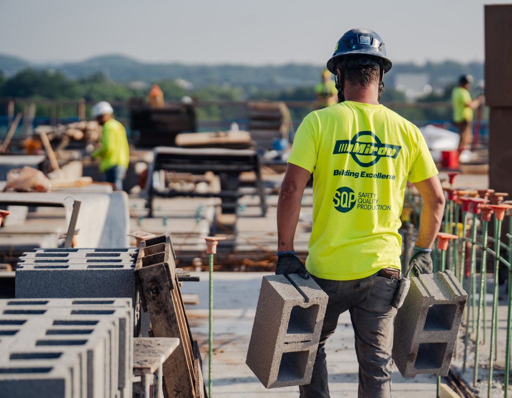 Miron laborer carrying concrete blocks across a jobsite