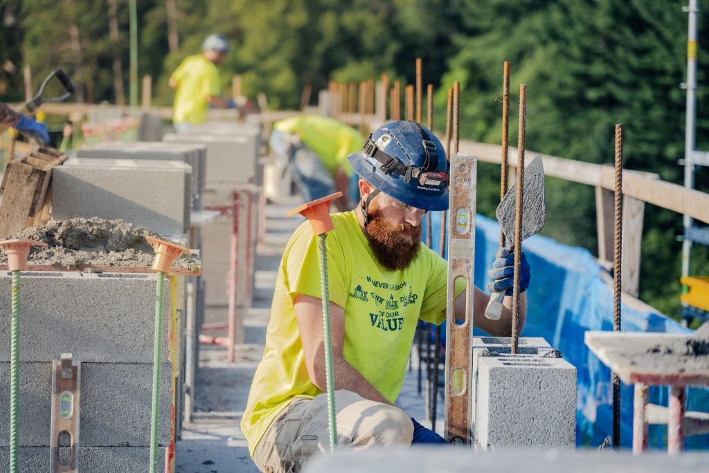 Miron mason laying concrete block on a wall