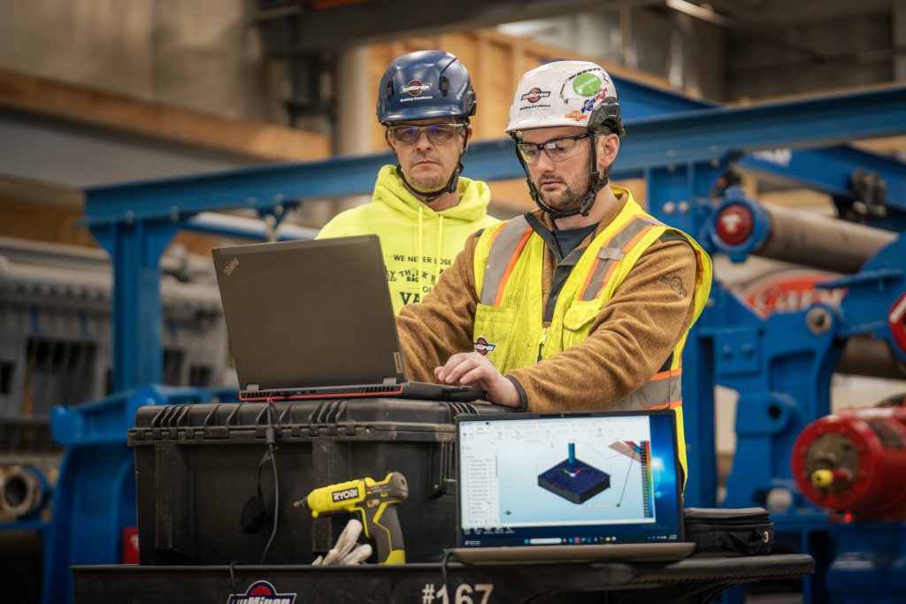 Miron millwrights reviewing a laptop beside equipment