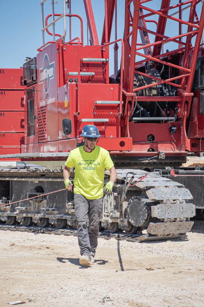 Miron operating engineer walking in front of a crawler crane