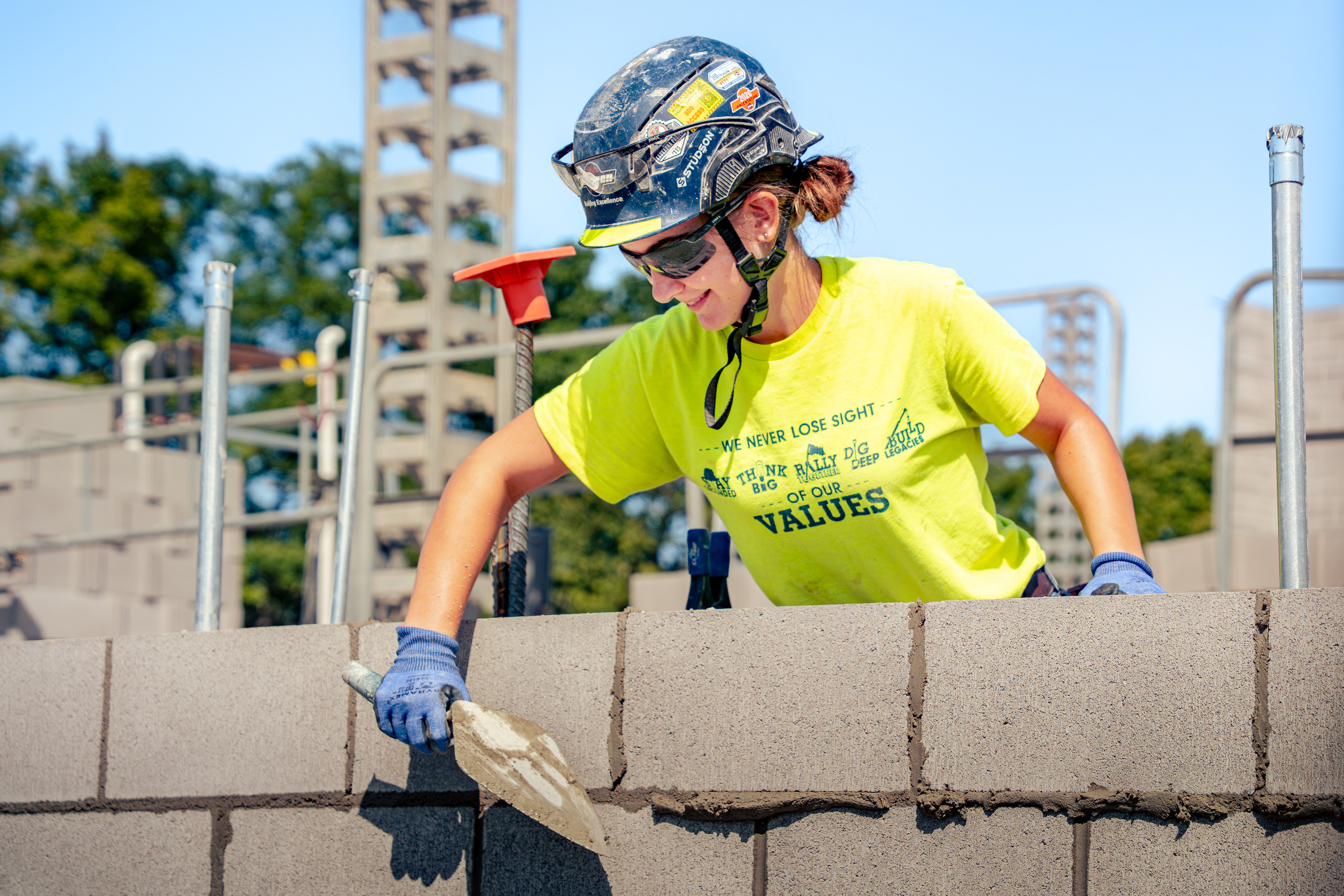 Youth apprentice laying mortar on a concrete block wall
