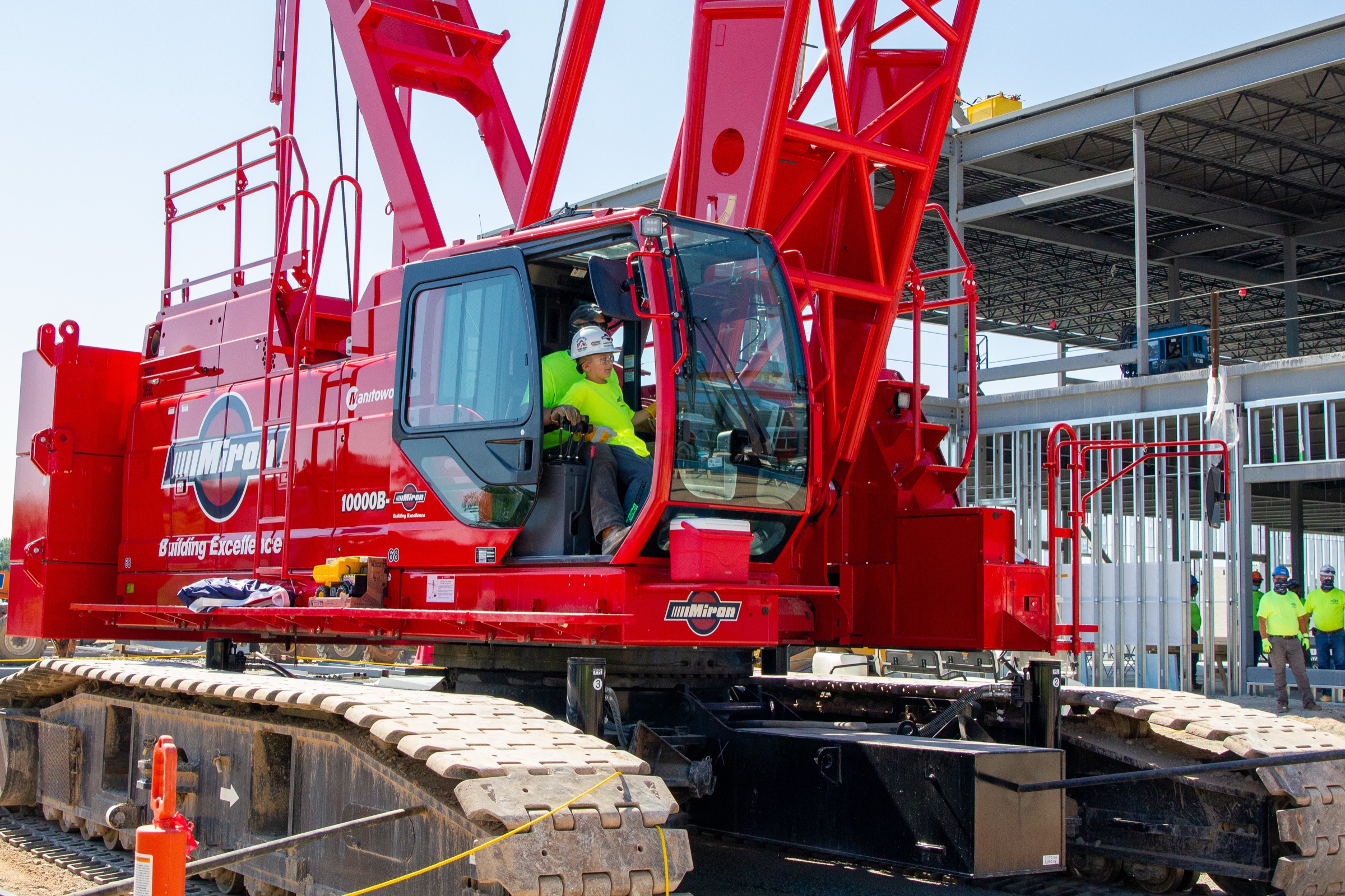 Young boy in a hard hat at the controls of a red Miron crawler crane